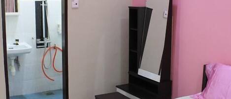 A bedroom with a pink bedspread, a black wardrobe, and a mirror.