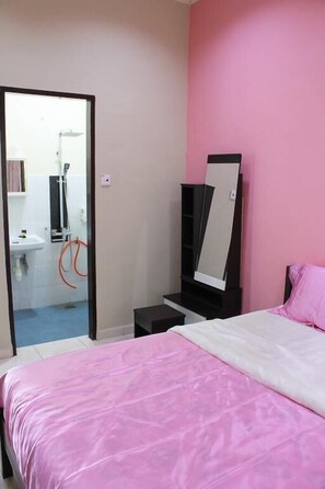 A bedroom with a pink bedspread, a black wardrobe, and a mirror.