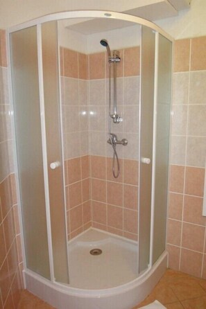A corner shower with glass doors and a showerhead. - Hotel ALFONSKA (Benecko)