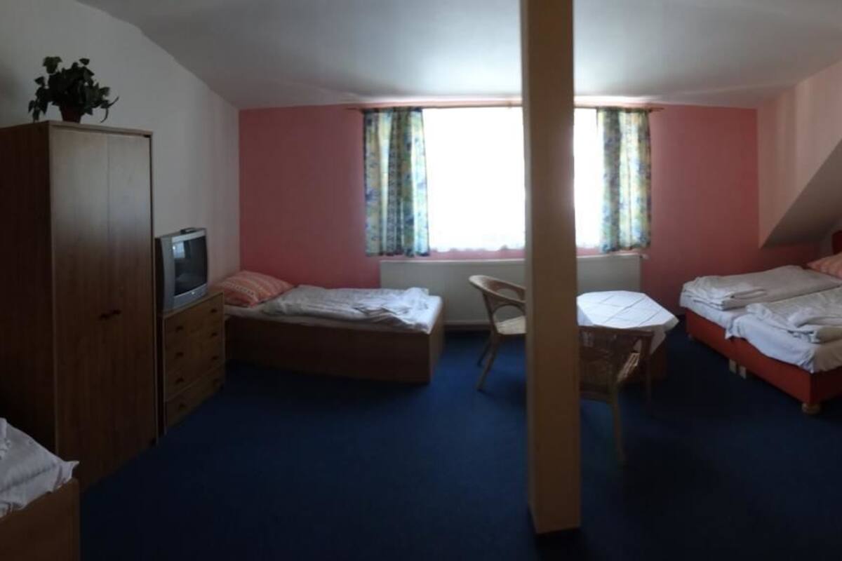A room with two beds, a desk, a wardrobe, and a television.