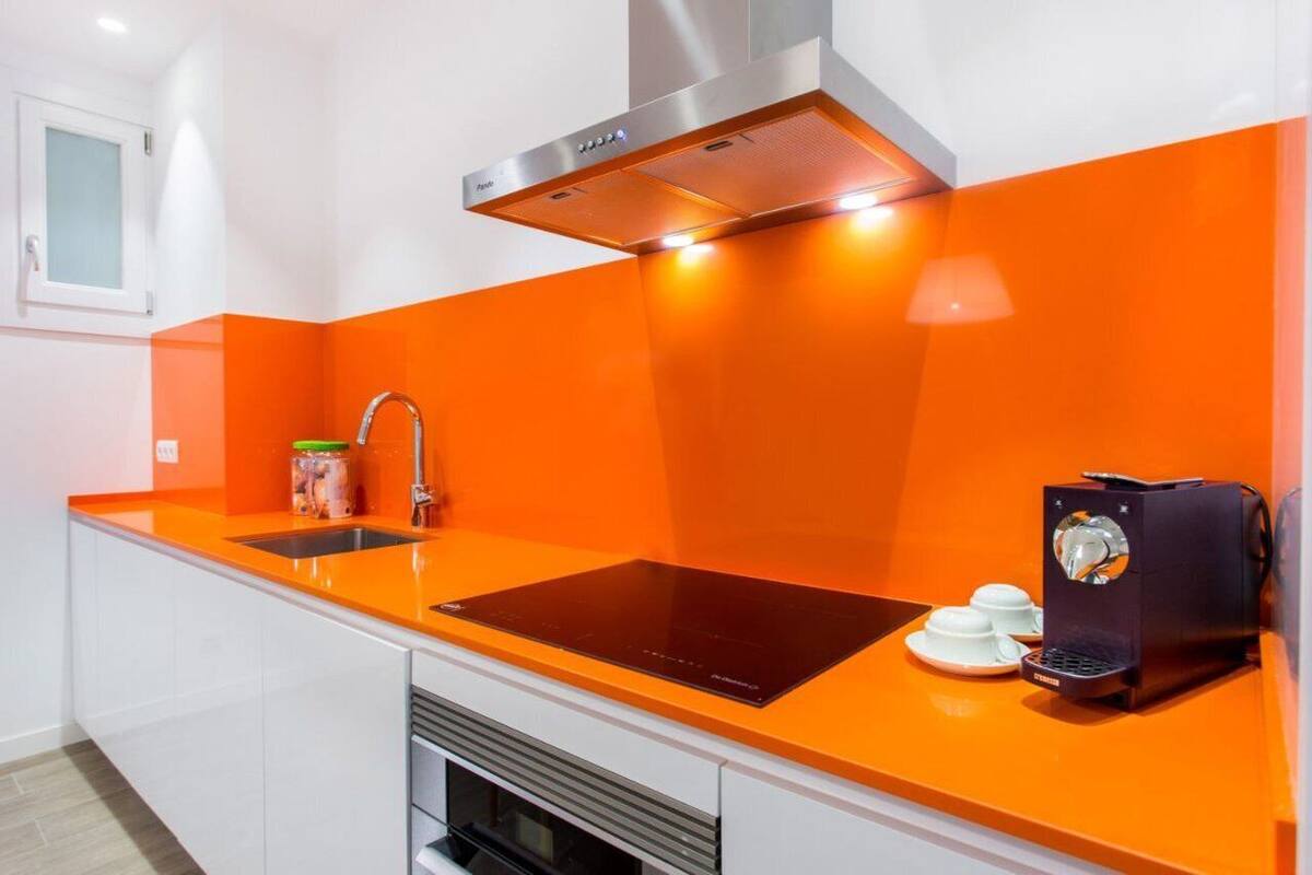A modern kitchen with a black induction cooktop, a stainless steel range hood, and a coffee machine.