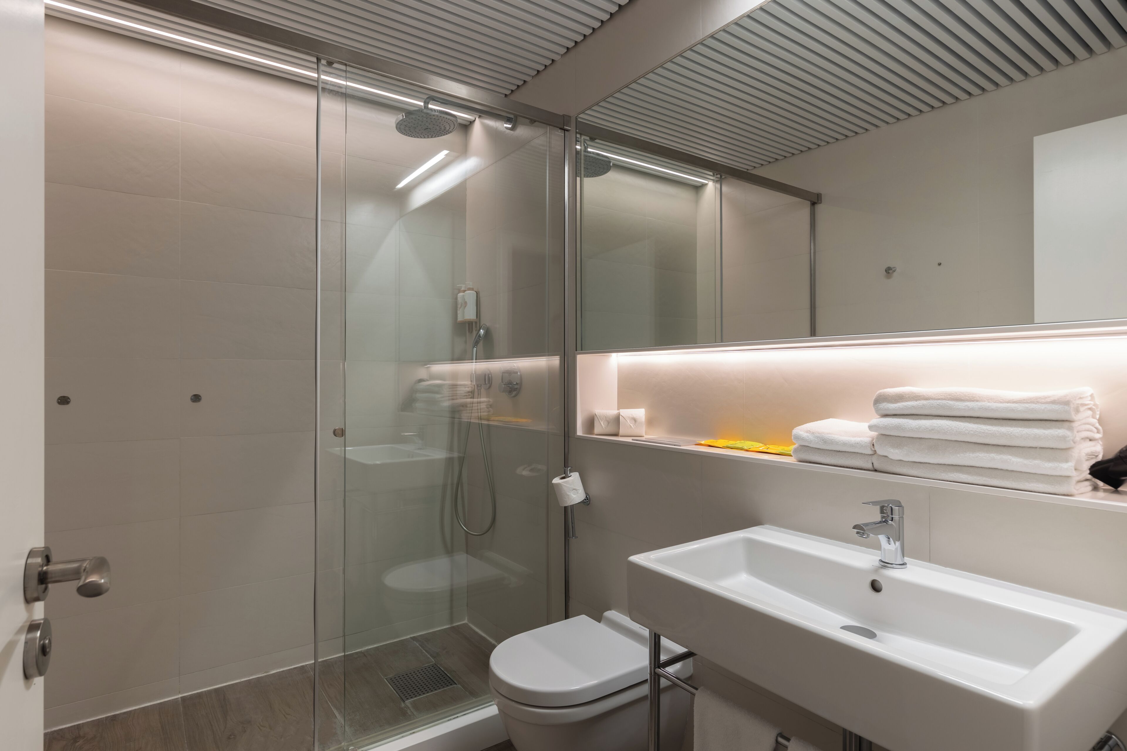 Un bagno moderno con doccia vetro, lavandino bianco e water.