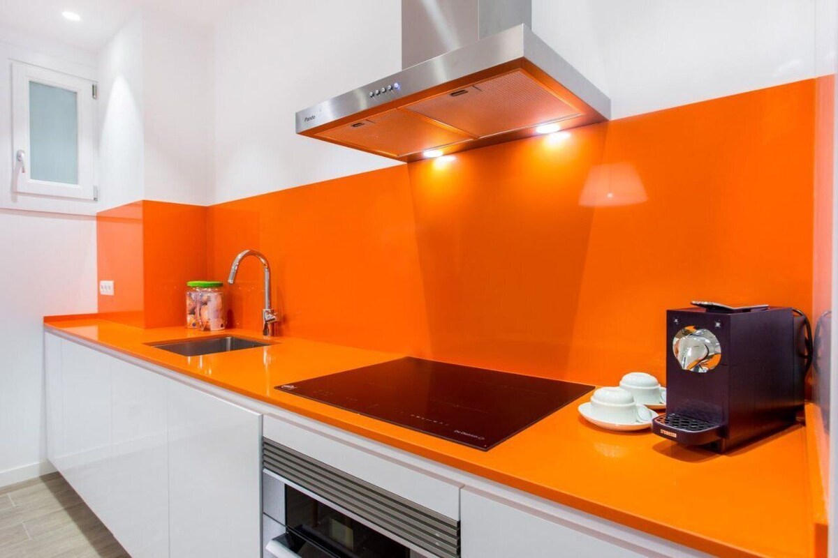 A modern kitchen with a black induction cooktop, a stainless steel range hood, and a coffee machine.