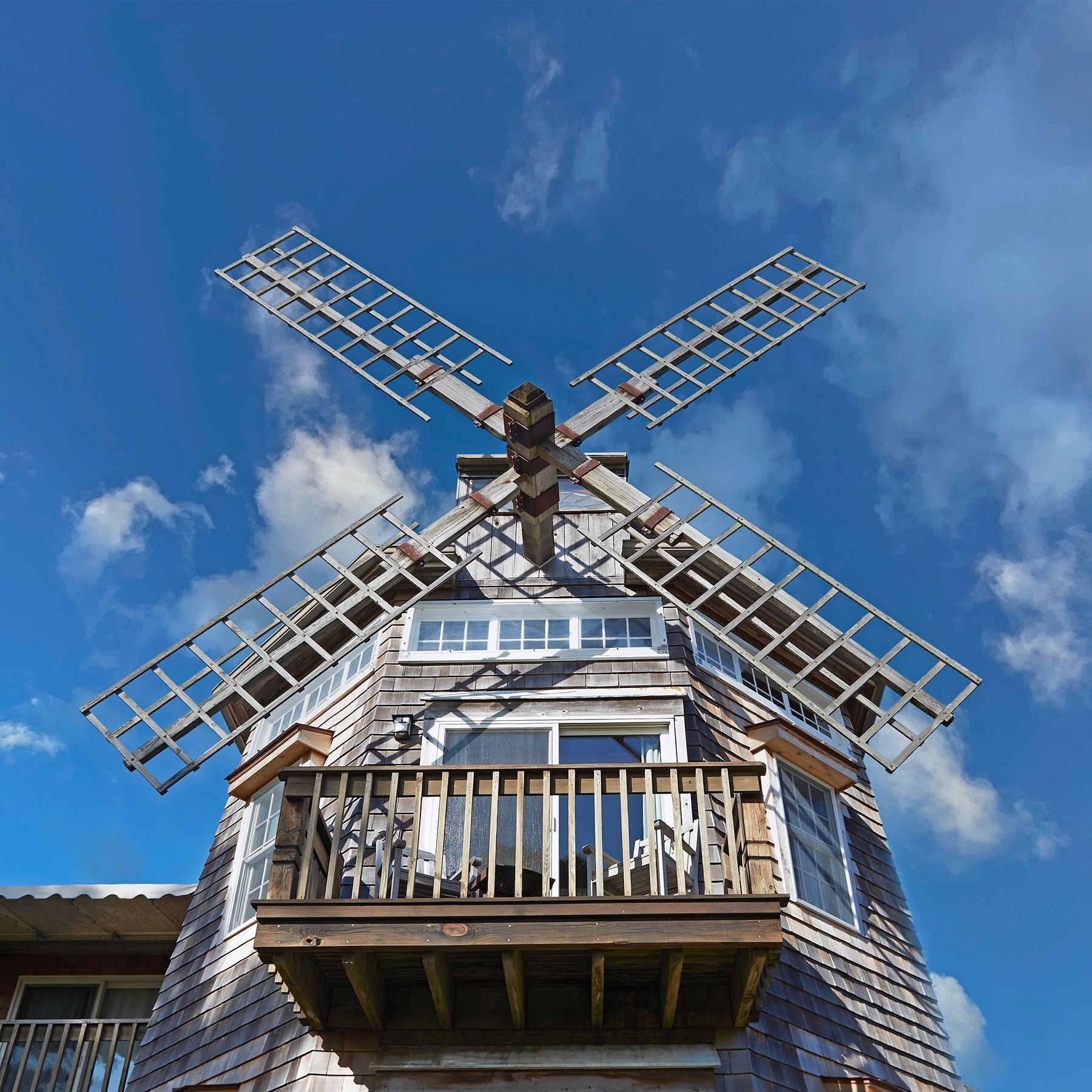 A windmill with a balcony, wooden structure, and windows.