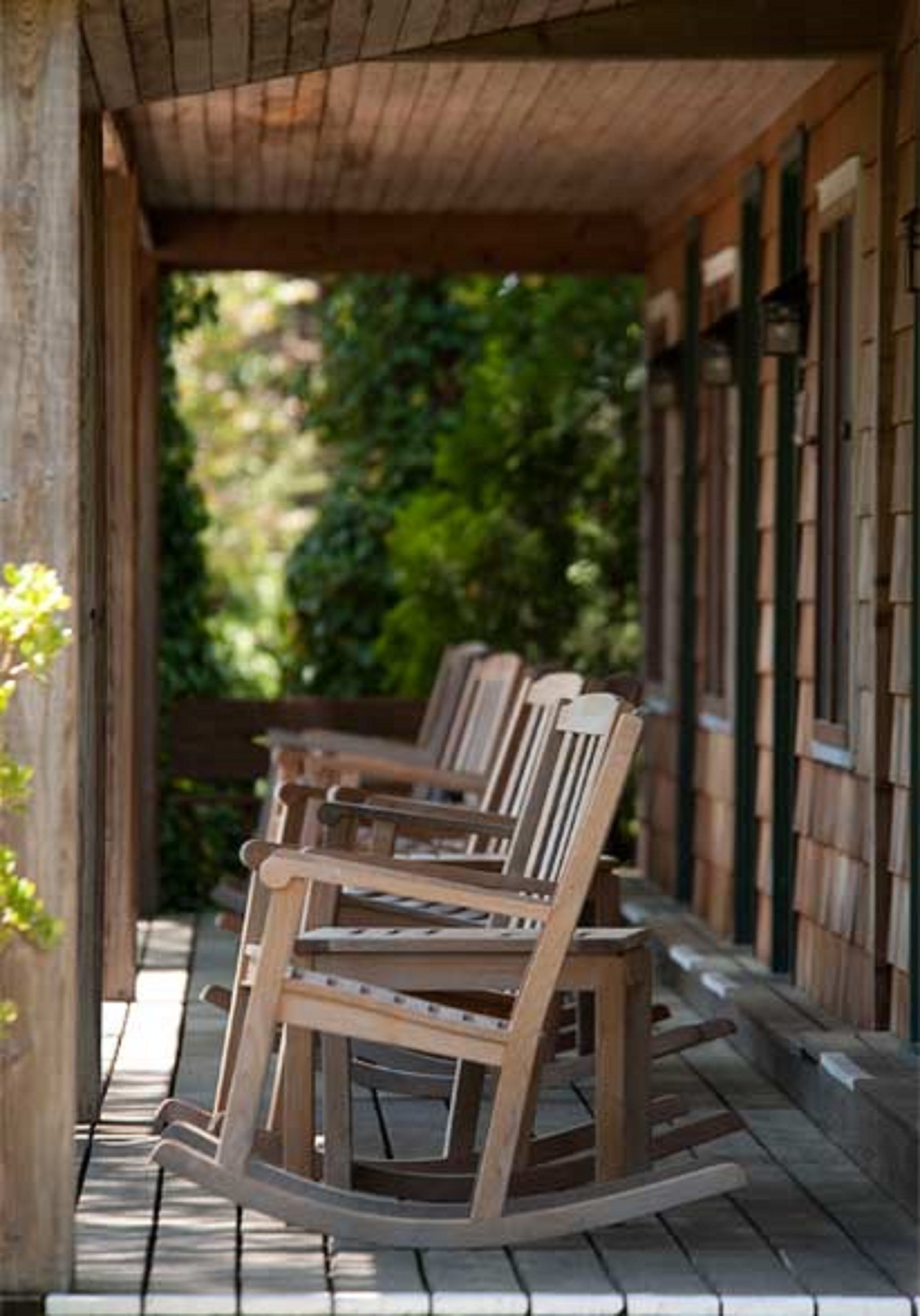 A wooden porch with rocking chairs and a wooden fence.