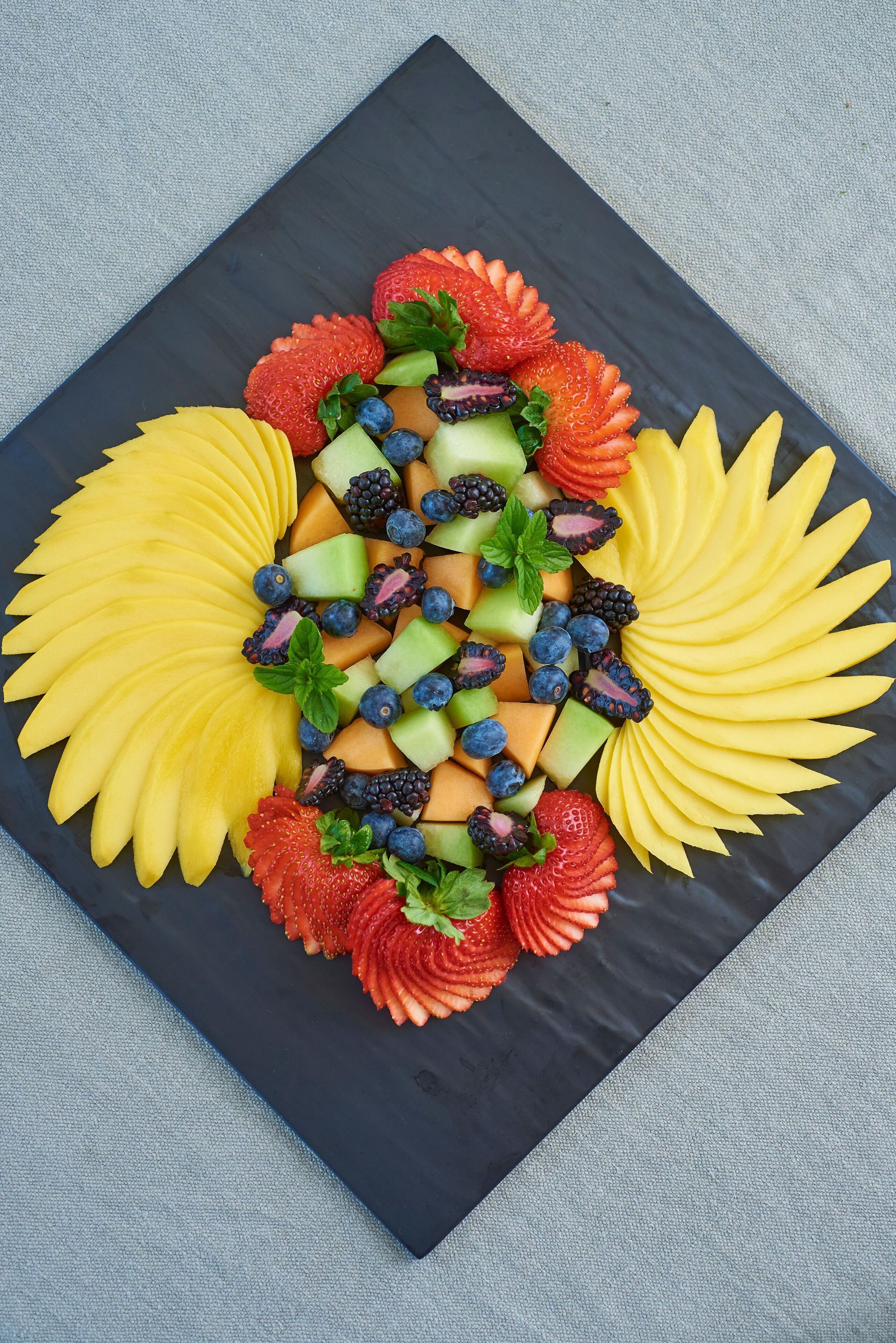 Um prato preto quadrado com uma composição de frutas.