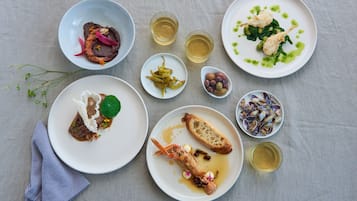 Una mesa con diversos platos, entre ellos mariscos, verduras y un recipiente pequeño de aceitunas.