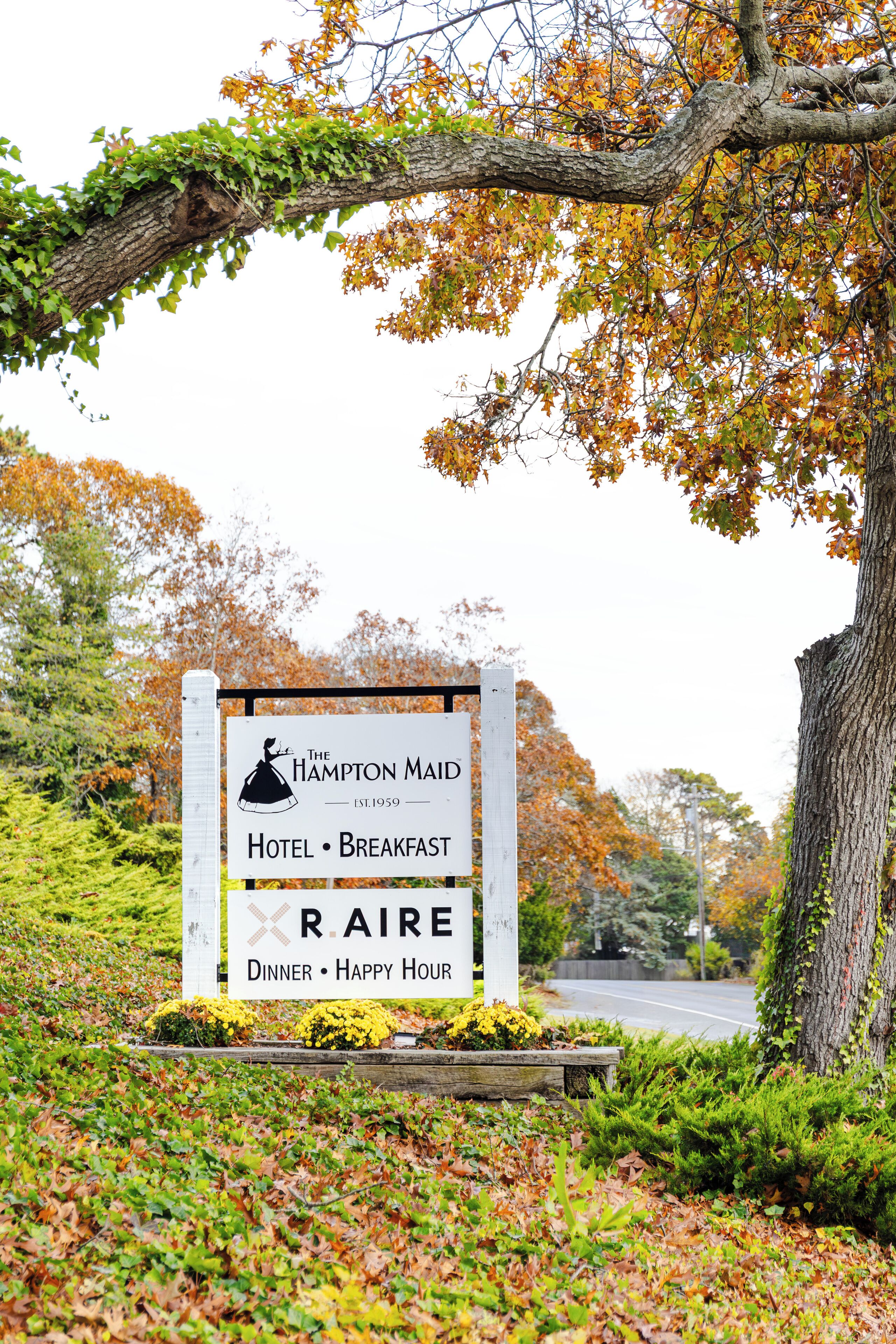 A sign for The Hampton Maid Hotel, indicating it offers breakfast, dinner, and happy hour.