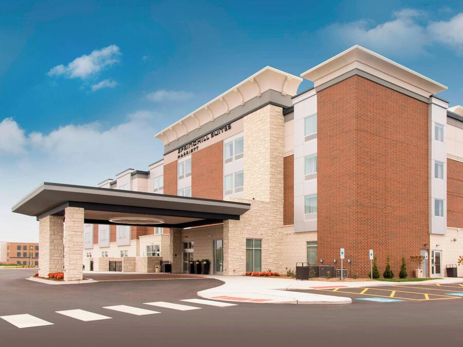 A modern hotel with a brick facade, a covered entrance, and a clear sky.