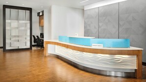 A reception desk with a modern design, a nameplate, and a patterned wall in the background. - SpringHill Suites Chicago Southeast/Munster IN (Munster)
