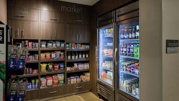 Interior de una tienda de comestibles con armarios de madera y secciones refrigeradas llenas de diversos productos.