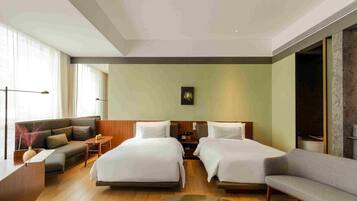 Una habitación de hotel con dos camas, un sofá, un escritorio y un ventanal grande.