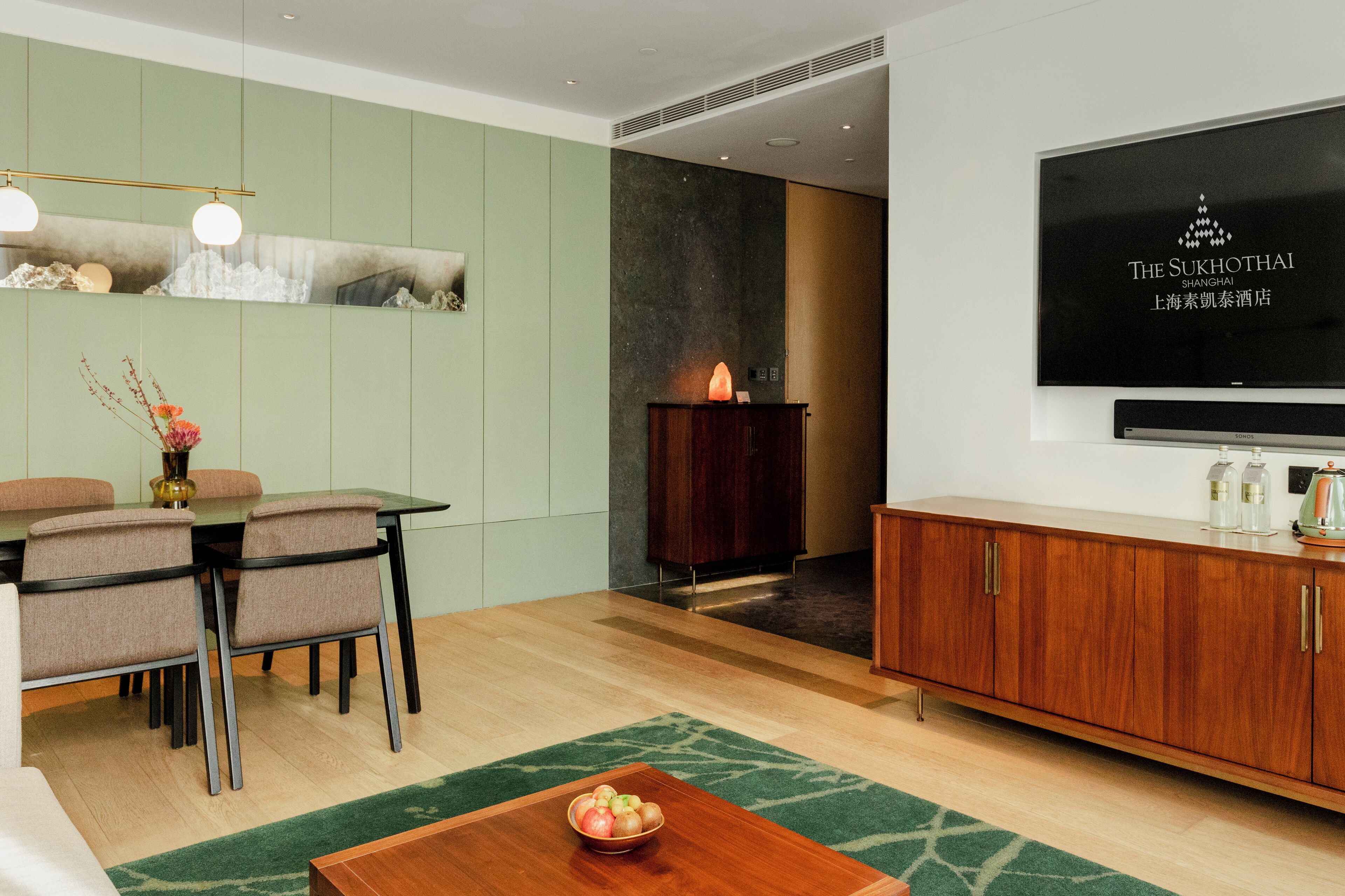 A modern living room with a dining area, a fireplace, a television, and a green rug.