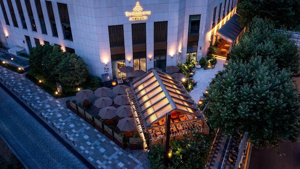 Een modern hotel met een opvallende entree, een terras en een goed verlichte gevel.