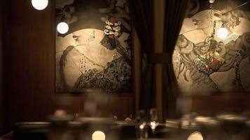 Un restaurante tenuemente iluminado con arte tradicional en las paredes y una mesa dispuesta para comer.