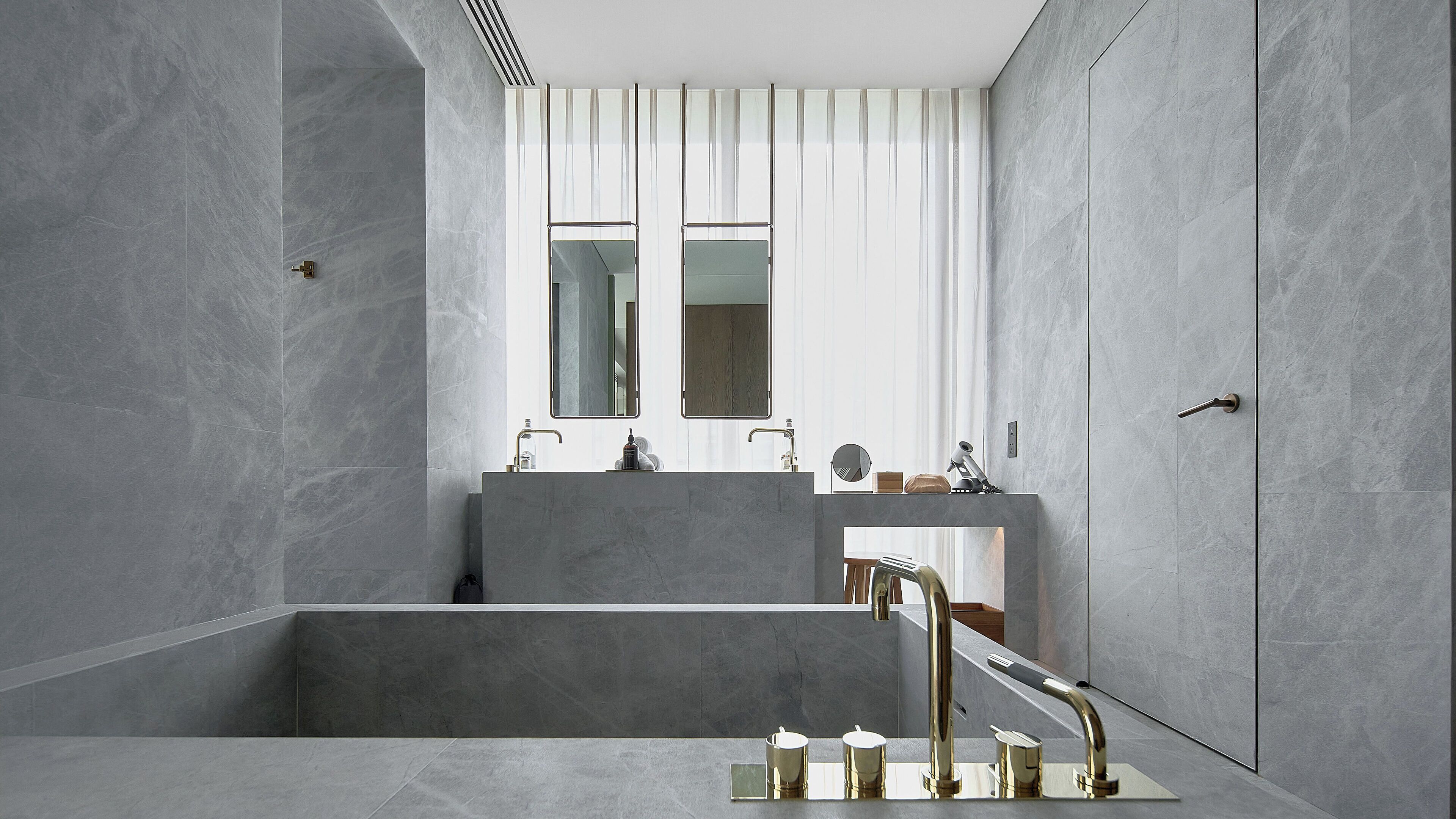 A modern bathroom with a large mirror, two sinks, and a bathtub.