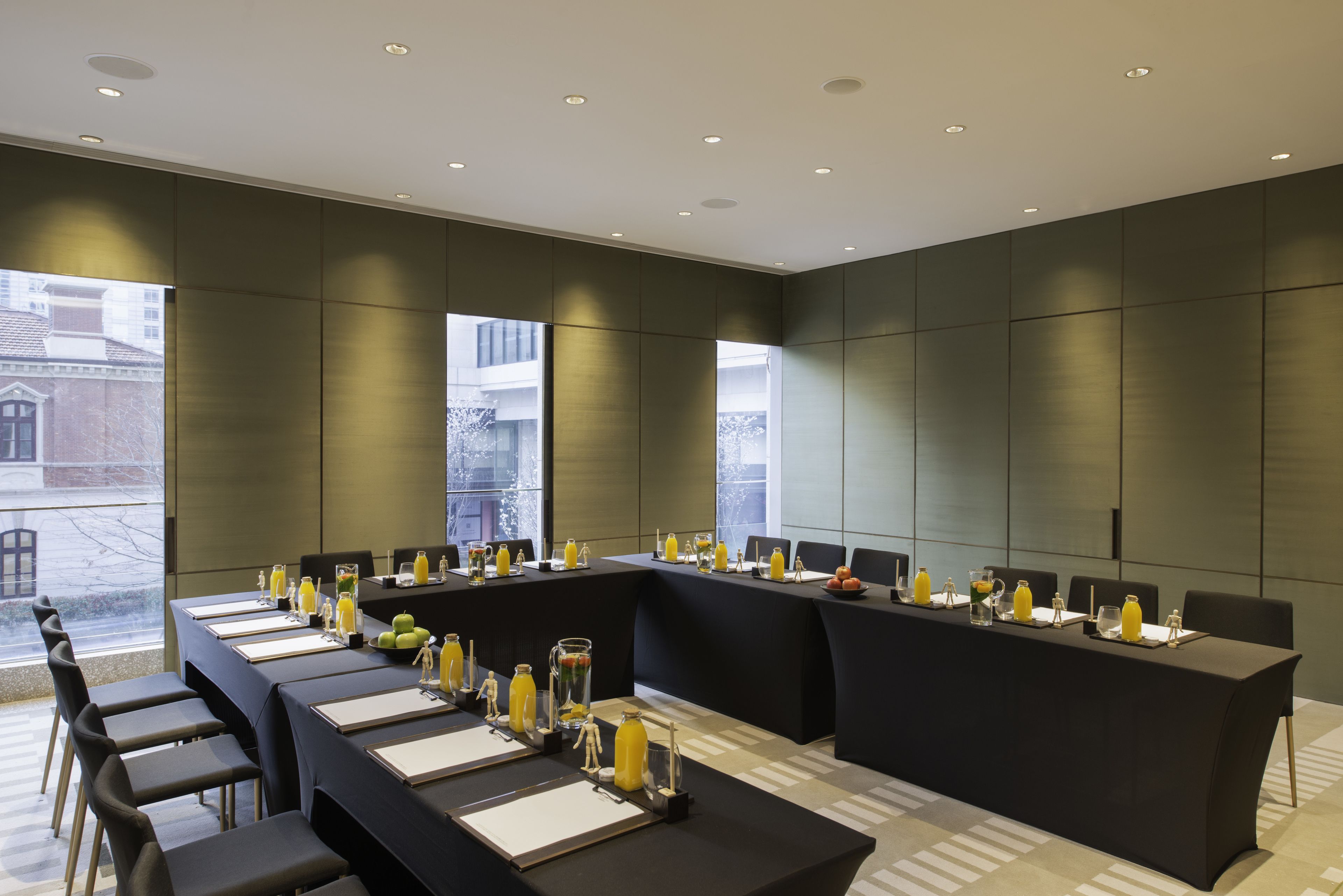 A conference room with a long table, chairs, and various items like water bottles and fruit.