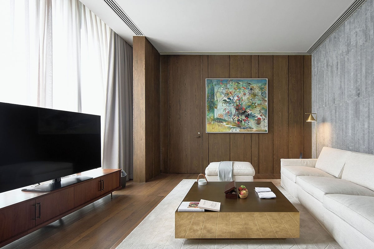 A modern living room with a flat-screen TV, a sofa, a coffee table, and a painting on the wall.