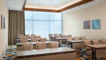 A conference room with multiple tables and chairs, large windows, and a patterned carpet.