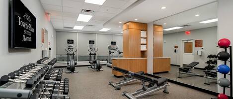 A gym with weight machines, cardio equipment, and a reception desk.