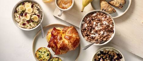 A breakfast spread with various dishes including oatmeal, coffee, a croissant, and a banana.