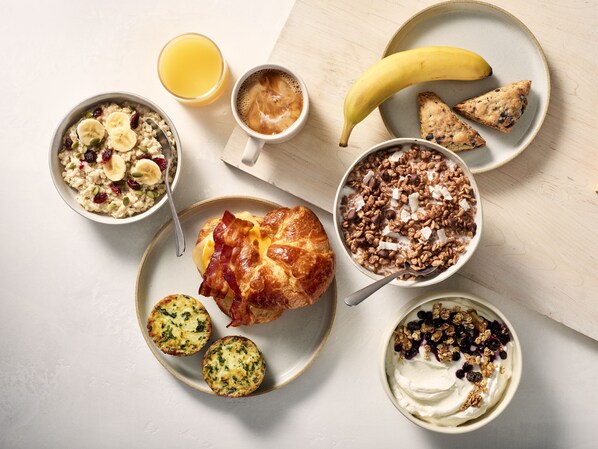 A breakfast spread with various dishes including oatmeal, coffee, a croissant, and a banana. - TownePlace Suites Fort Worth University Area/Medical Center (Fort Worth)