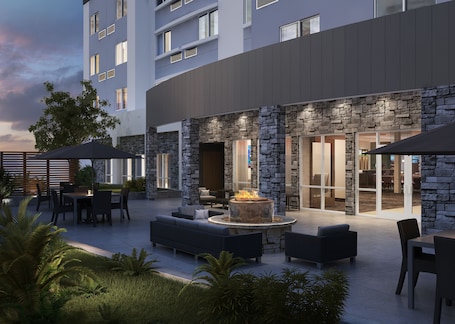 A modern outdoor patio area with stone walls, a fire pit, and outdoor seating.