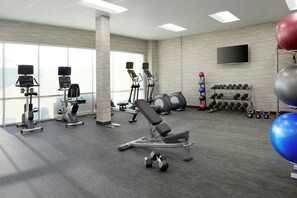 Un gimnasio con máquinas de cardio, mancuernas y pelotas de ejercicio.