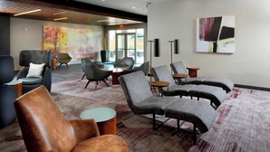 Ein stilvoller Lounge-Bereich mit Ledermöbeln und Stoffpolstern, einem großen abstrakten Gemälde und Blick ins Freie.