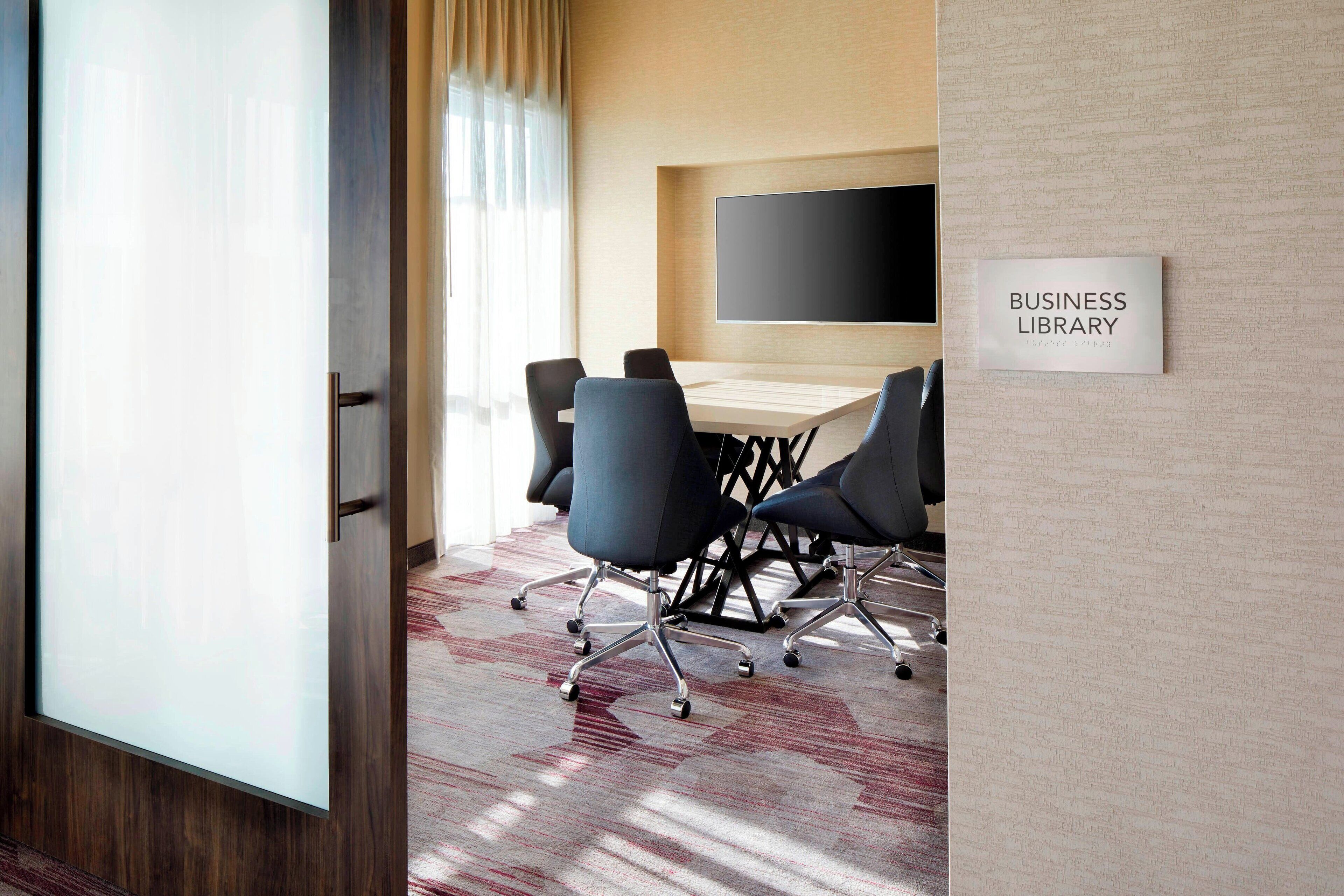 A business library with a conference table, chairs, and a sign on the wall.