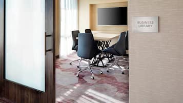 A business library with a conference table, chairs, and a sign on the wall.
