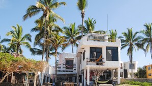 A beachfront property with a two-story building, a hammock, and palm trees. - Hostal Galapagos by Bar de Beto (Puerto Villamil)