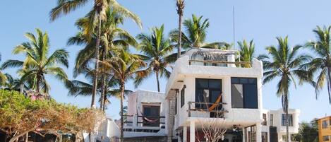 A beachfront property with a two-story building, a hammock, and palm trees.