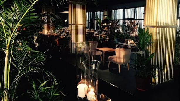 An indoor space with a modern design, featuring tall columns, glass furniture, and lush greenery. - Royal Grand Hotel (Monrovia)