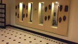 A hallway with a tiled floor and wooden panels with mirrors and masks. - Royal Grand Hotel (Monrovia)