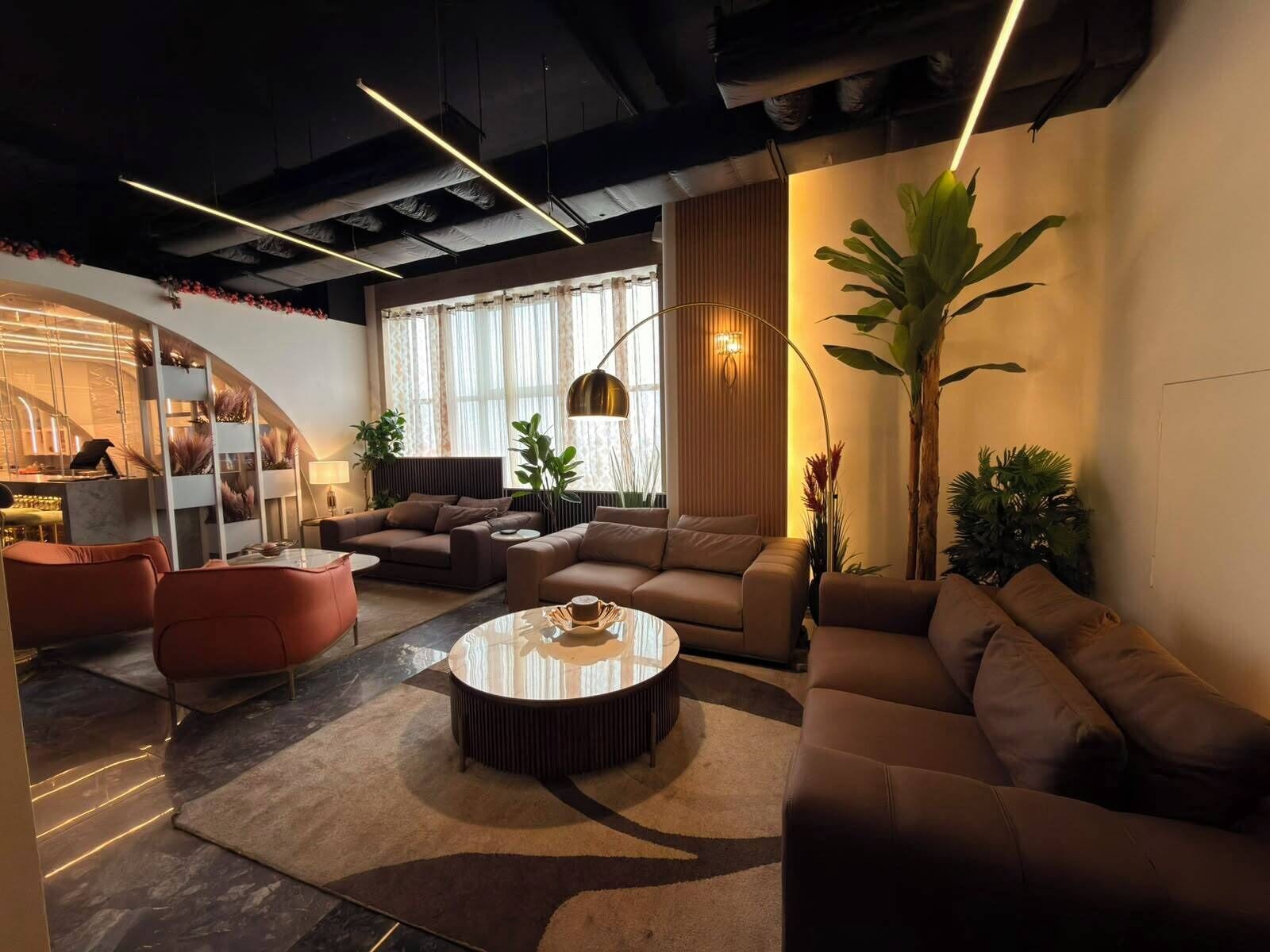 Una sala moderna con una mesa de centro redonda, sofás y una planta grande.