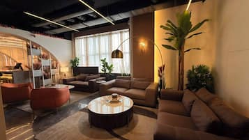 Una sala moderna con una mesa de centro redonda, sofás y una planta grande.