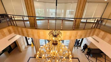 A grand chandelier in a spacious lobby with a high ceiling and large windows.