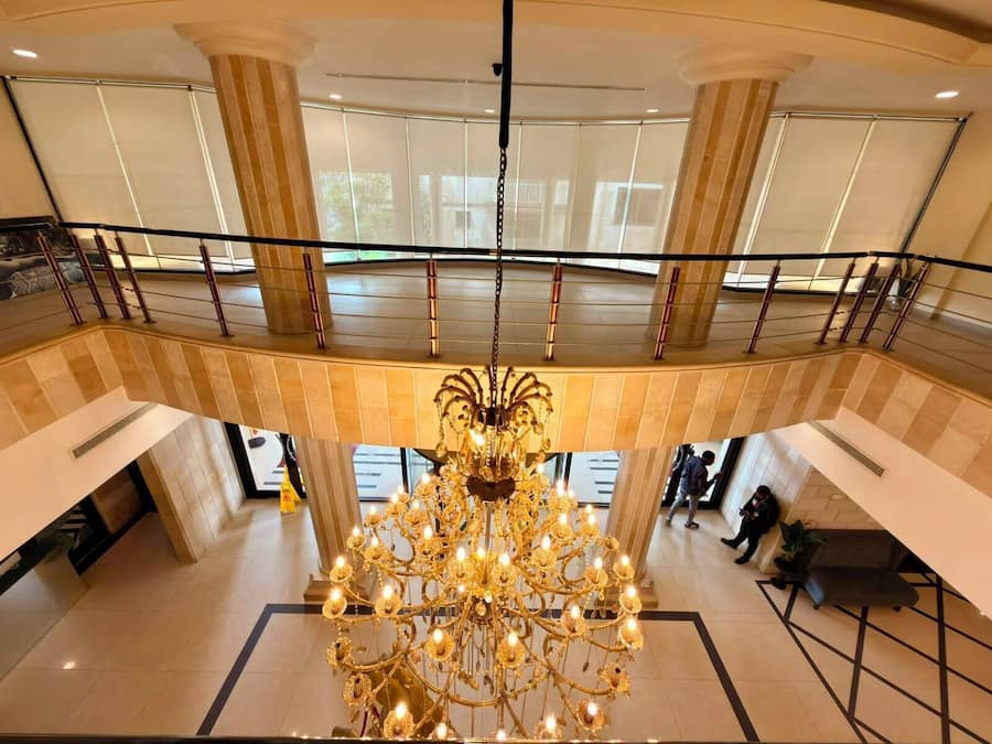 A grand chandelier in a spacious lobby with a high ceiling and large windows.