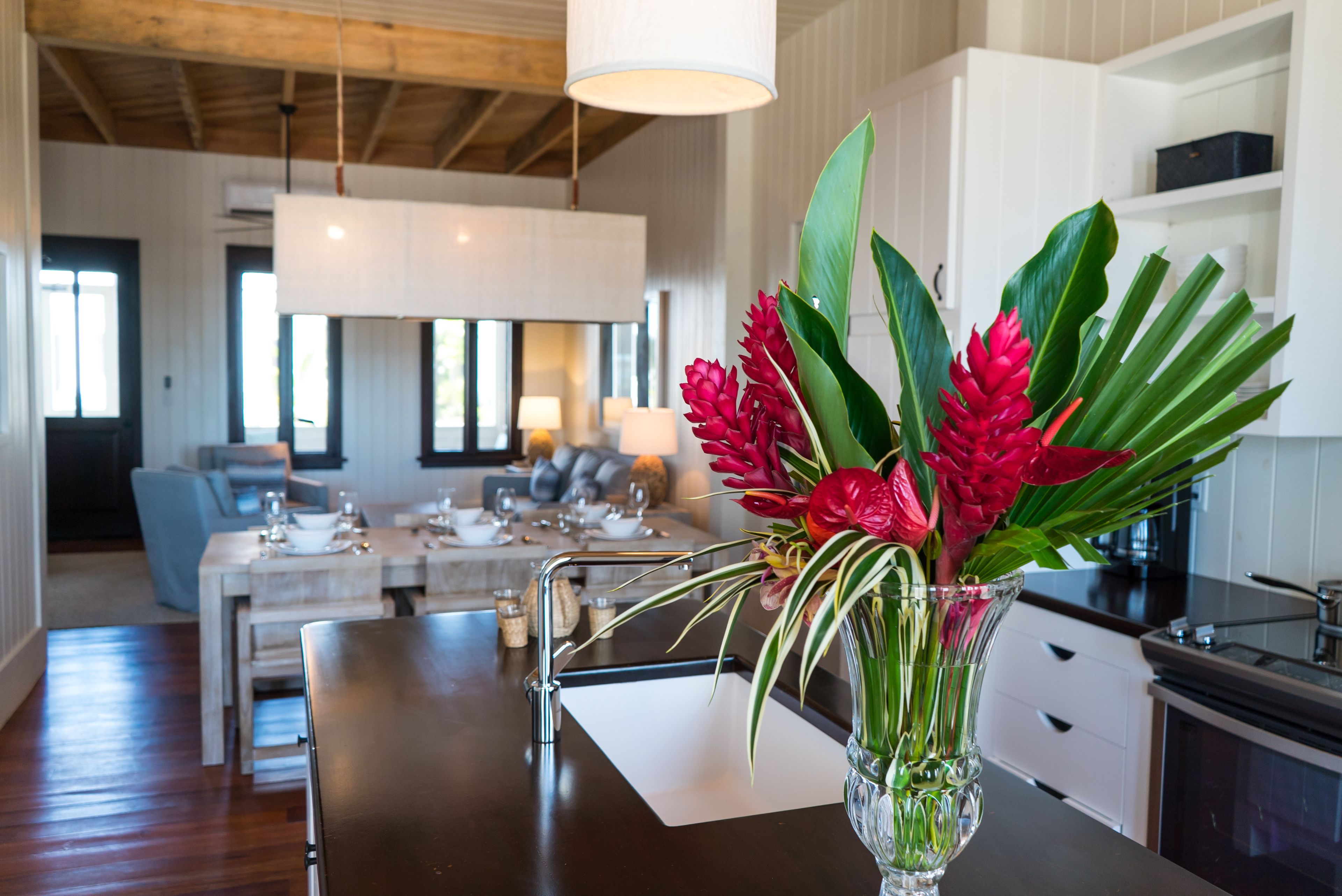 A modern kitchen with a central island, a dining area with a table and chairs, and a living space with a sofa and a coffee table.