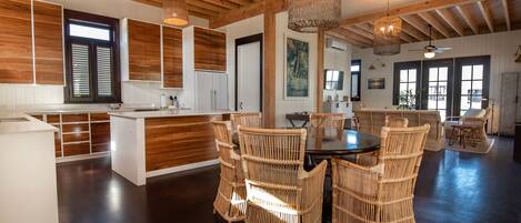 A spacious kitchen with wooden cabinets, a dining area with wicker chairs, and a large island.