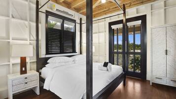 A bedroom with a four-poster bed, a nightstand, a wardrobe, and a window with shutters.