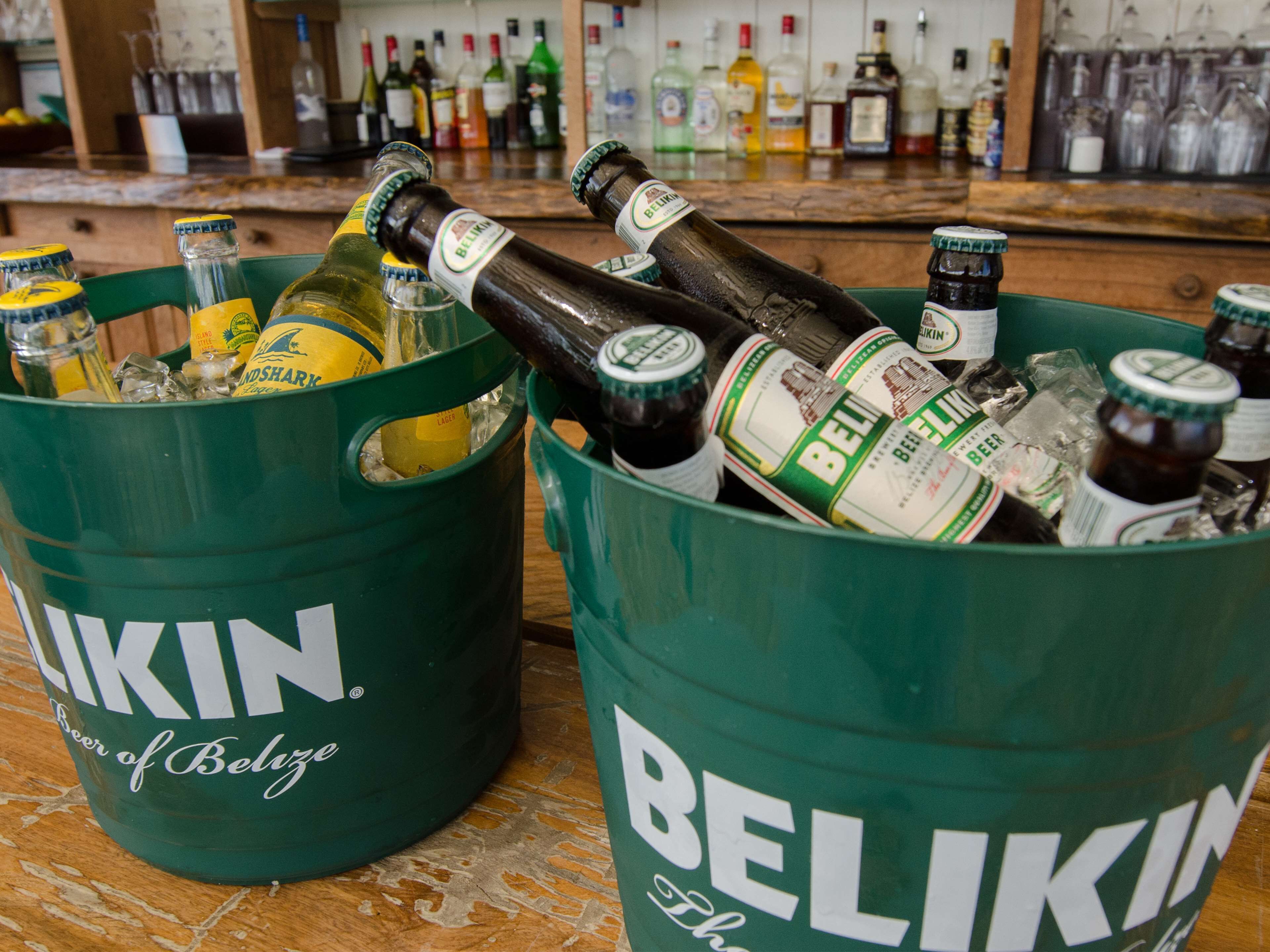 Dos baldes verdes llenos de varias botellas de cerveza Belikin y otras bebidas.