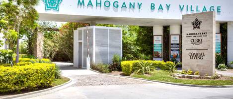 L’entrée de Mahogany Bay Village est signalée par un panneau indiquant le nom et les logos du complexe hôtelier et du club de plage.