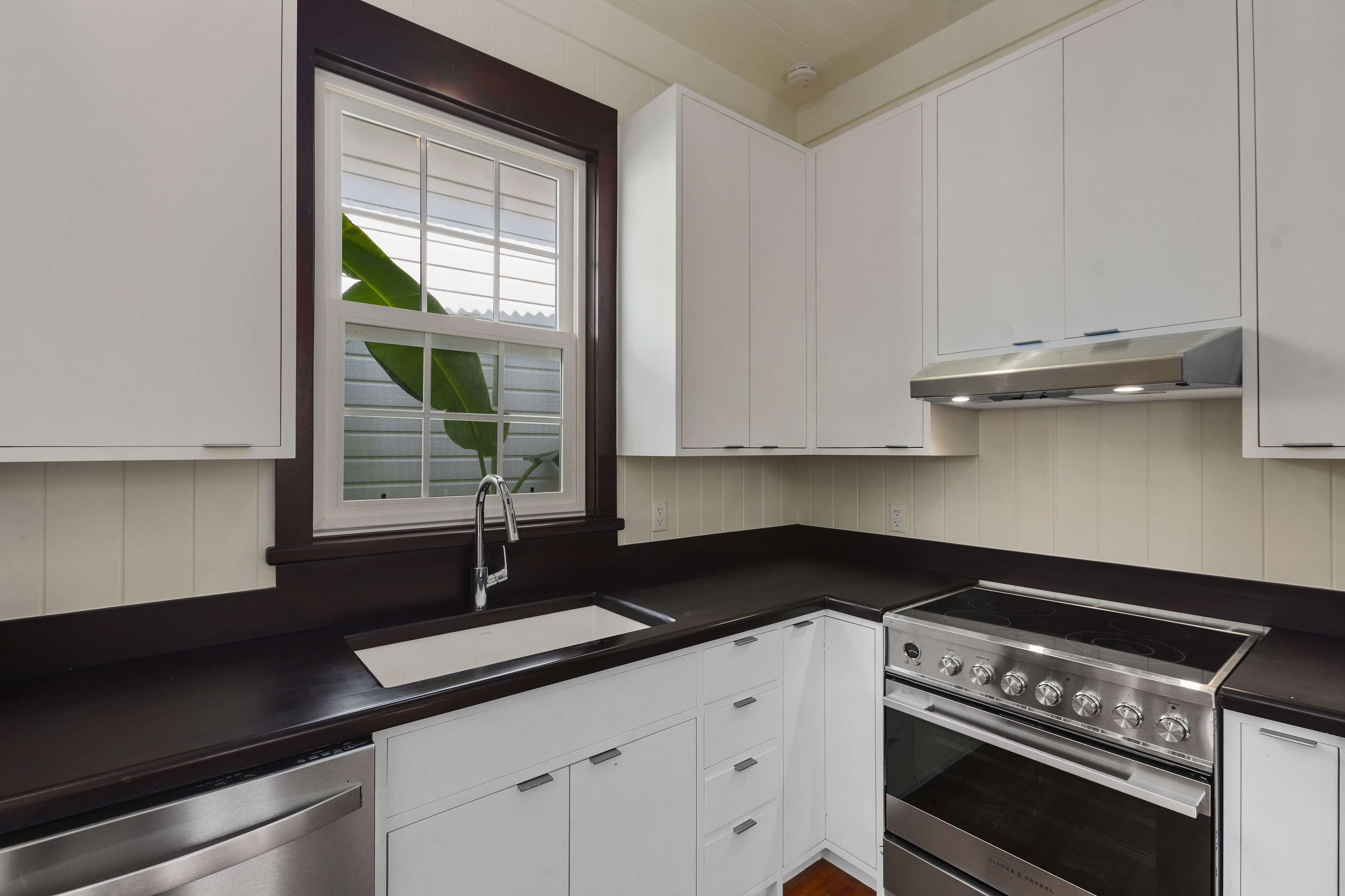 A modern kitchen with white cabinetry, a stainless steel stove, and a black countertop.