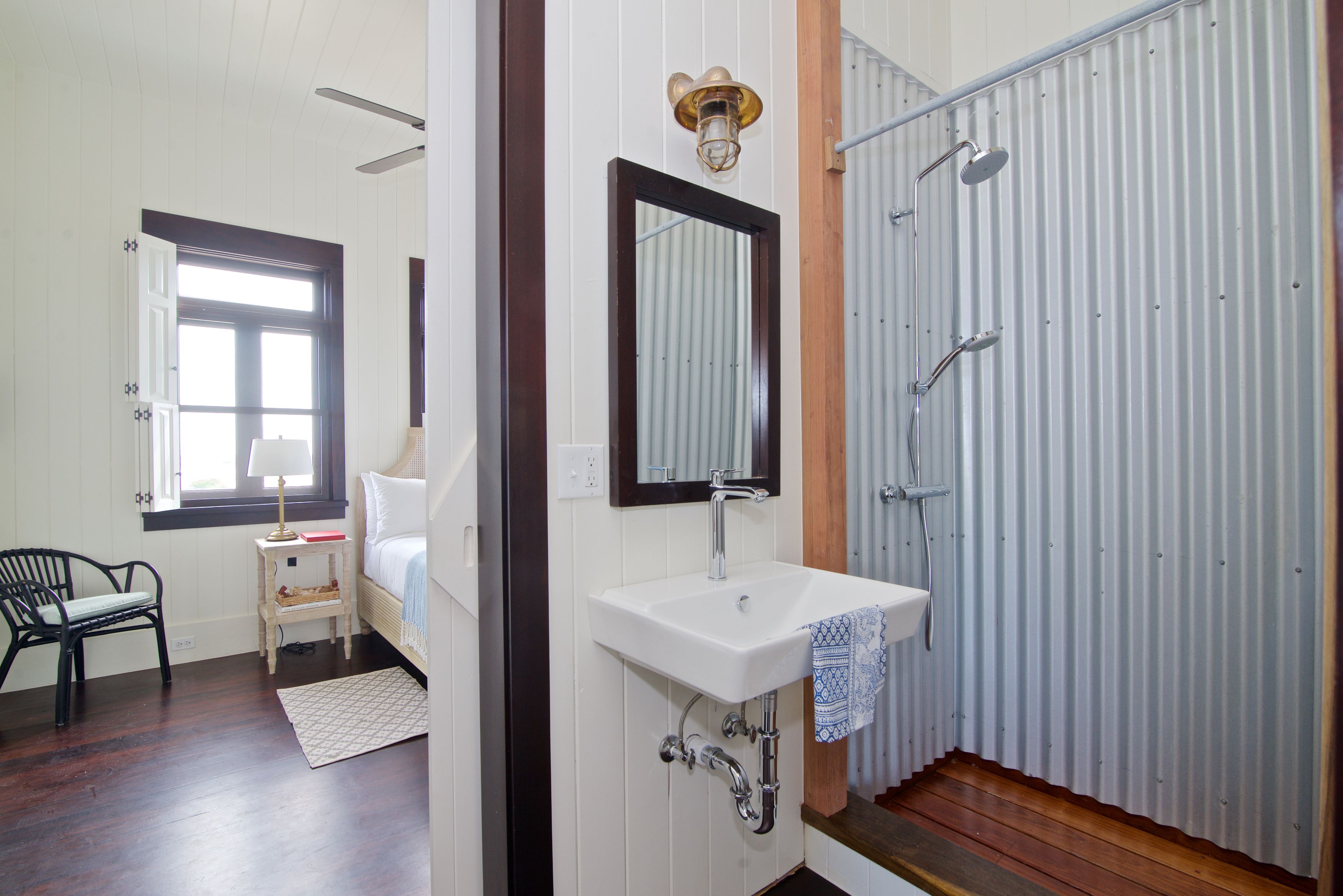 A bathroom with a white sink, a mirror, a shower, and a window.