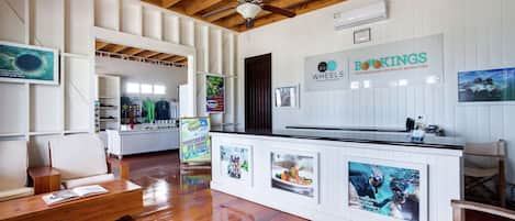 A reception area with a wooden ceiling, white walls, a reception desk, and seating.