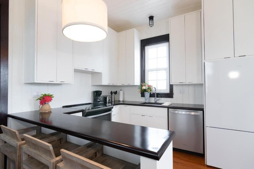 A modern kitchen with white cabinets, a black countertop, and a central island with seating.