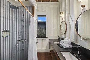 A bathroom with a shower, a window with blinds, a sink with a mirror, and towels on the counter. - Mahogany Bay Resort & Beach Club, Curio Collection by Hilton (San Pedro)