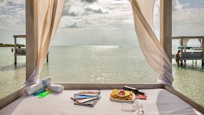 Ein Zimmer mit Bett, einem gedeckten Tisch und Meerblick.